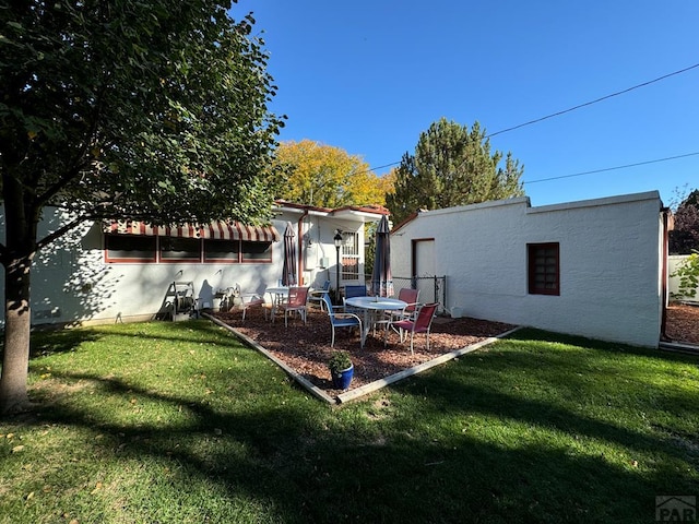 back of property featuring stucco siding and a lawn
