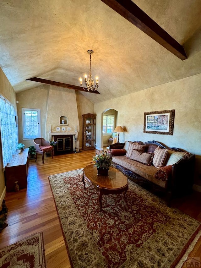 living area with arched walkways, a chandelier, wood finished floors, lofted ceiling, and baseboards