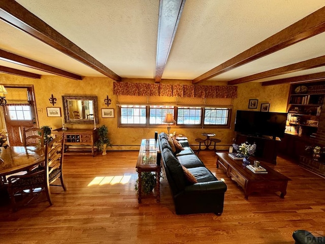 living room featuring a textured ceiling, wood finished floors, a baseboard heating unit, and beam ceiling