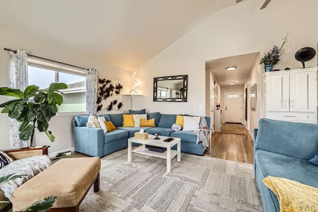 living area featuring high vaulted ceiling, light wood-style flooring, and baseboards