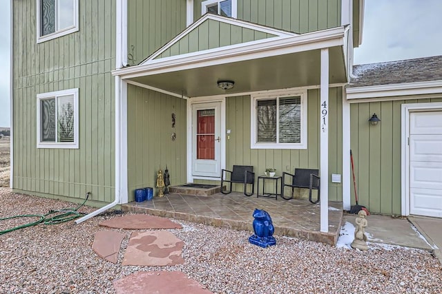 property entrance featuring a garage, covered porch, and roof with shingles