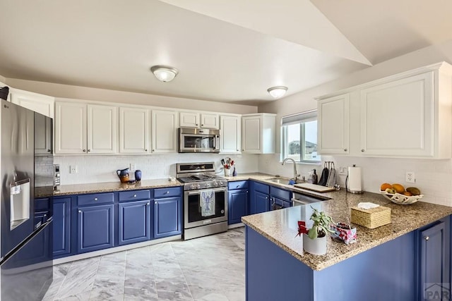 kitchen featuring blue cabinetry, stainless steel appliances, white cabinetry, a sink, and a peninsula