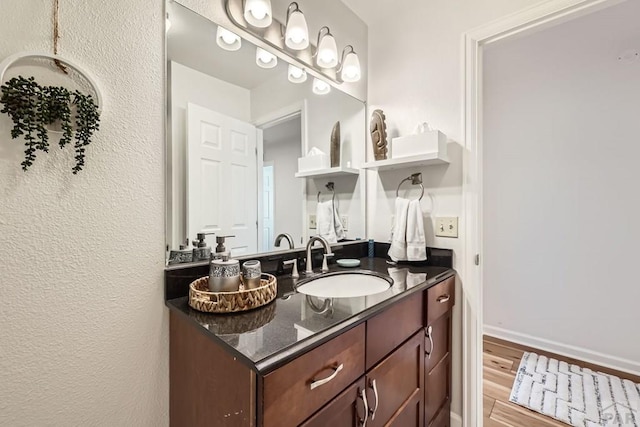 bathroom featuring baseboards, wood finished floors, and vanity