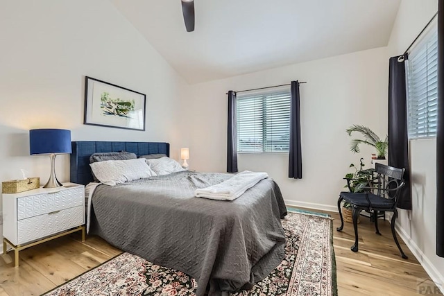 bedroom with light wood-style floors, lofted ceiling, ceiling fan, and baseboards