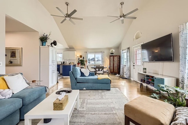 living area with ceiling fan, high vaulted ceiling, and light wood-style floors