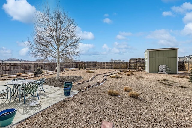 view of yard with an outbuilding, outdoor dining area, a fenced backyard, a shed, and a patio area