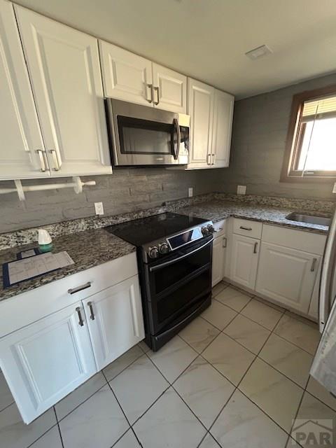21 Terrace Dr, Pueblo, CO 81001 - kitchen featuring stainless steel microwave, electric stove, white cabinets, and tasteful backsplash