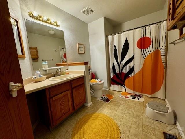 full bathroom featuring toilet, visible vents, and vanity