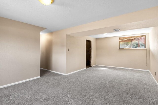 unfurnished room featuring carpet floors, visible vents, a textured ceiling, and baseboards