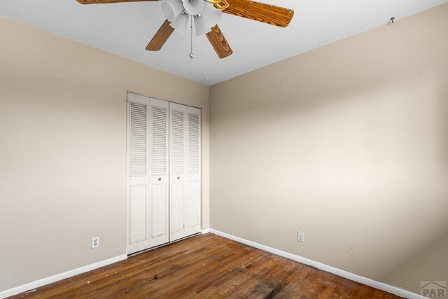 unfurnished bedroom with a ceiling fan, baseboards, dark wood finished floors, and a closet