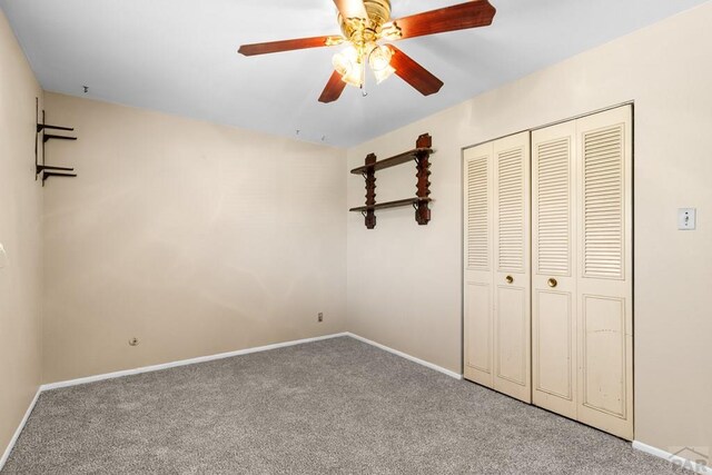 unfurnished bedroom with a closet, carpet flooring, a ceiling fan, and baseboards