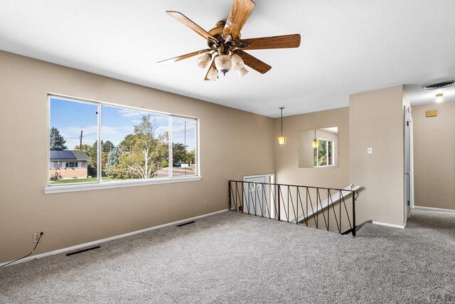 carpeted spare room with ceiling fan, visible vents, and baseboards