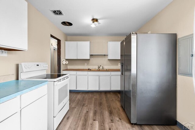 kitchen featuring white range with electric stovetop, stainless steel refrigerator with ice dispenser, visible vents, white cabinets, and a sink