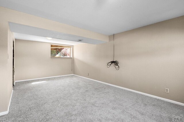 below grade area with carpet floors, visible vents, and baseboards