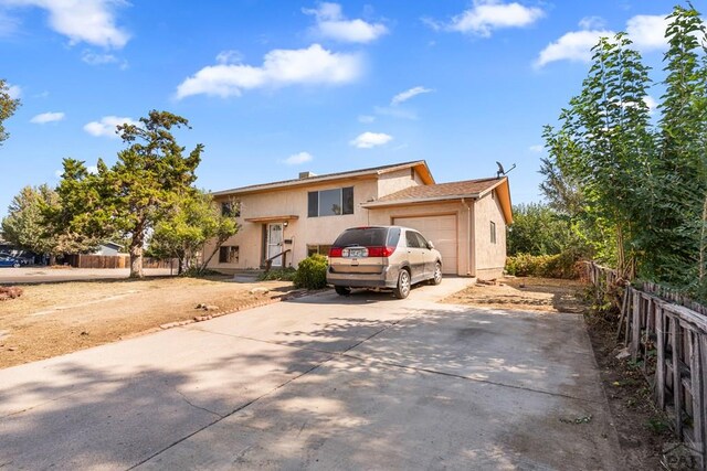 view of front of property featuring a garage, concrete driveway, fence, and stucco siding