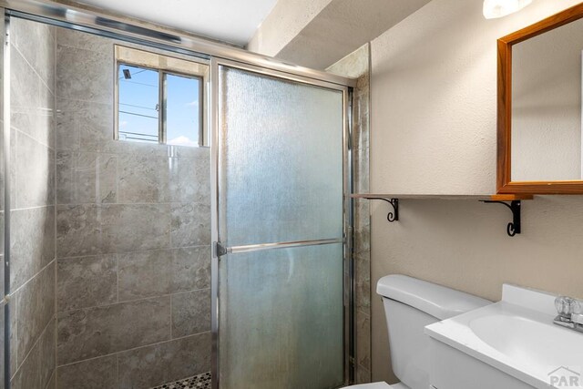 full bathroom with tiled shower, vanity, and toilet