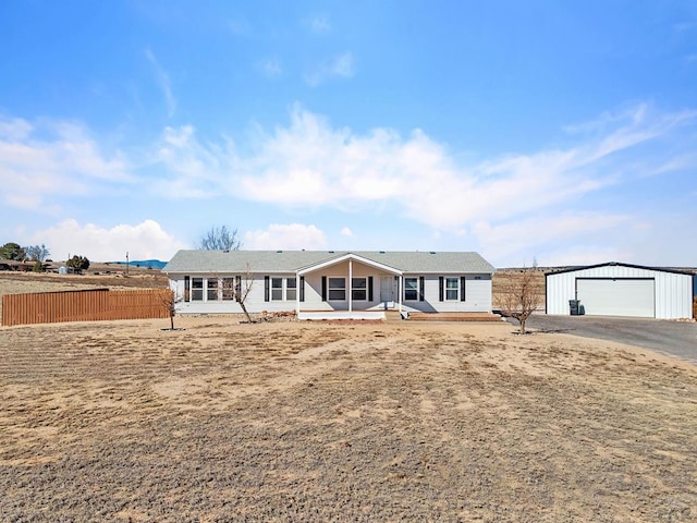 ranch-style home featuring a detached garage, fence, and an outdoor structure