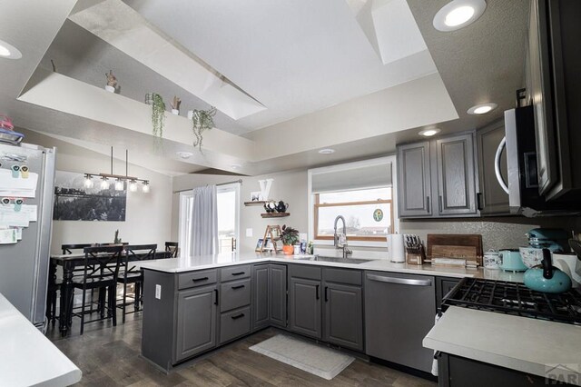 1108 W Meadowmoor Dr, Pueblo West, CO 81007 - kitchen featuring gray cabinets, a peninsula, light countertops, stainless steel appliances, and a sink