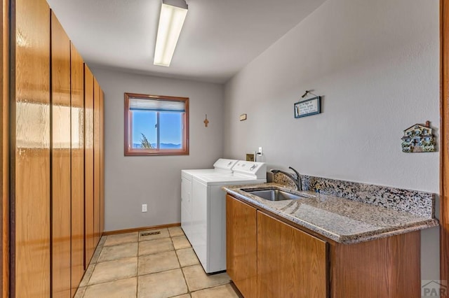 laundry area with light tile patterned flooring, a sink, baseboards, cabinet space, and washing machine and clothes dryer