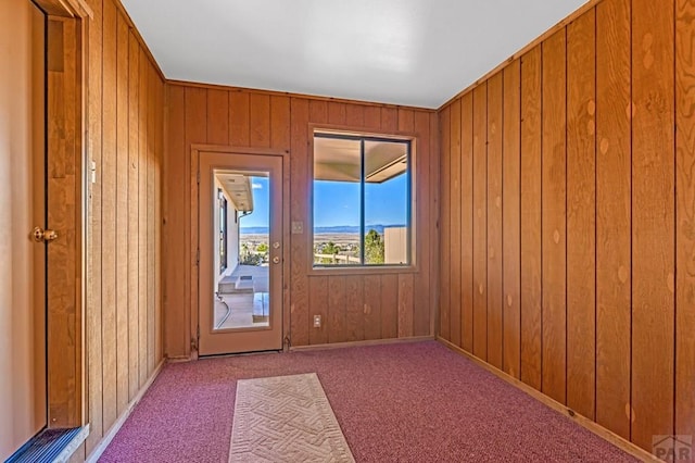 carpeted spare room featuring wood walls