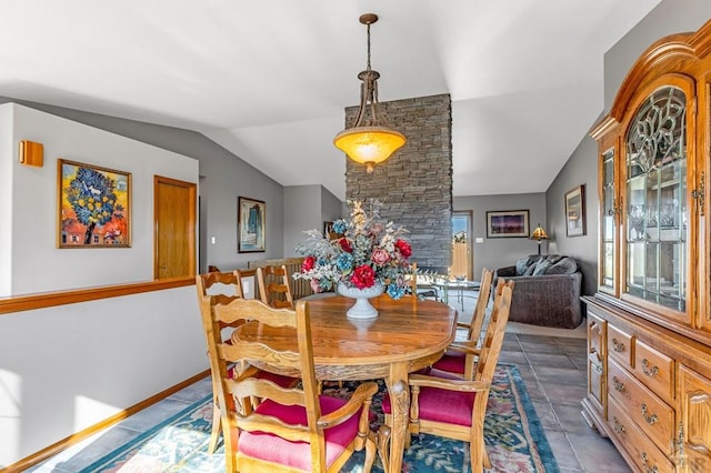 dining space featuring dark tile patterned flooring, vaulted ceiling, and baseboards