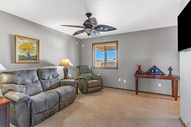 living area featuring light colored carpet, ceiling fan, and baseboards