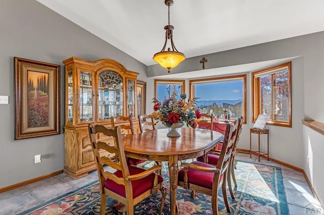 dining space featuring light tile patterned floors, baseboards, and vaulted ceiling