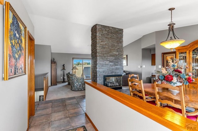 living room with dark tile patterned floors, vaulted ceiling, dark colored carpet, and a stone fireplace