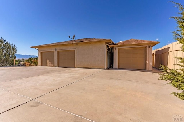 view of front facade featuring a garage, a mountain view, fence, and stucco siding