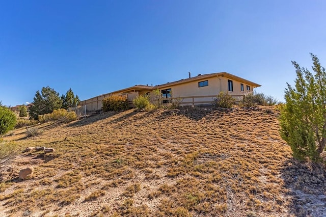 rear view of house featuring fence and stucco siding