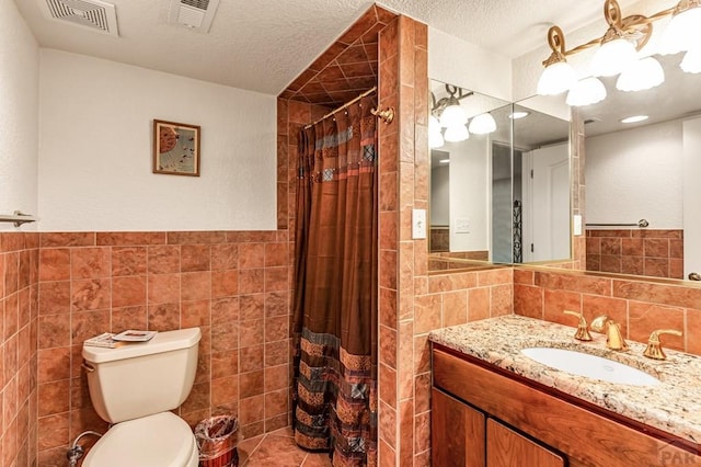 full bathroom with a textured ceiling, vanity, visible vents, and tile walls