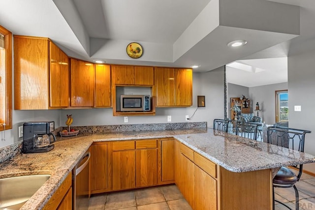 kitchen with a peninsula, appliances with stainless steel finishes, brown cabinets, and a kitchen breakfast bar