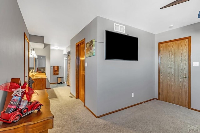 corridor with baseboards, visible vents, and light colored carpet