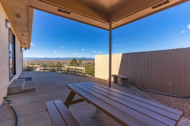 view of patio with a mountain view, fence, and visible vents