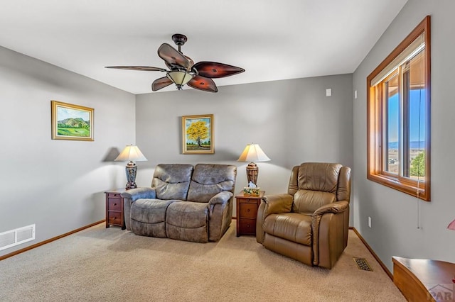 living area featuring baseboards, visible vents, ceiling fan, and light colored carpet