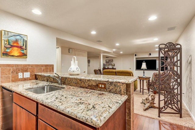 kitchen featuring light stone counters, visible vents, open floor plan, a sink, and dishwasher