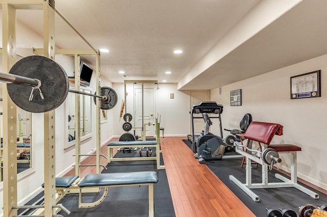 exercise area featuring baseboards, wood finished floors, and recessed lighting