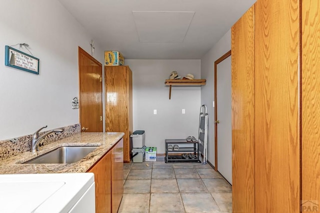 kitchen featuring light tile patterned floors, brown cabinets, a sink, and light stone countertops