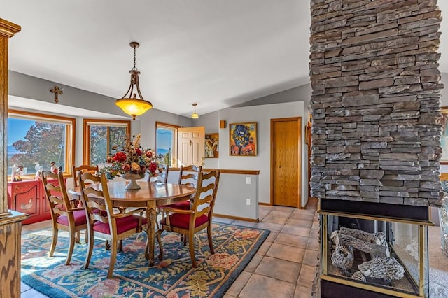 dining space with lofted ceiling, light tile patterned flooring, a fireplace, and baseboards