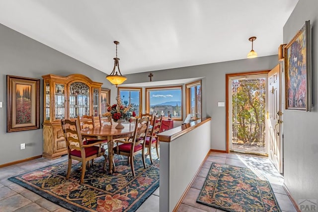 dining space featuring lofted ceiling, light tile patterned flooring, and baseboards