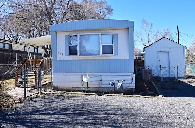 view of front of property with fence, an outdoor structure, and a storage unit