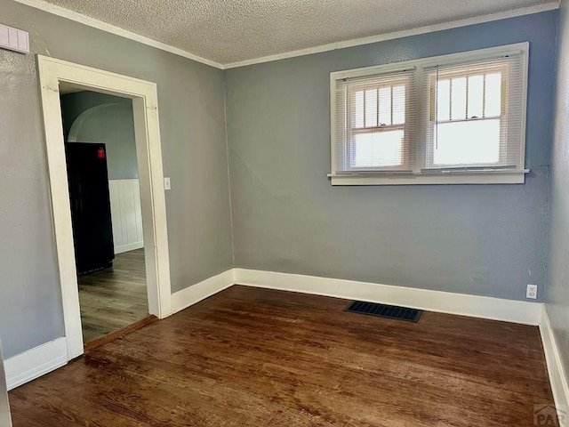 410 W 25th St, Pueblo, CO 81003 - spare room featuring ornamental molding, wood finished floors, a textured ceiling, baseboards, and arched walkways