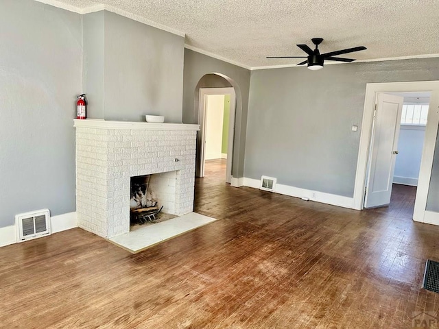 410 W 25th St, Pueblo, CO 81003 - unfurnished living room featuring ceiling fan, crown molding, a brick fireplace, wood finished floors, and arched walkways