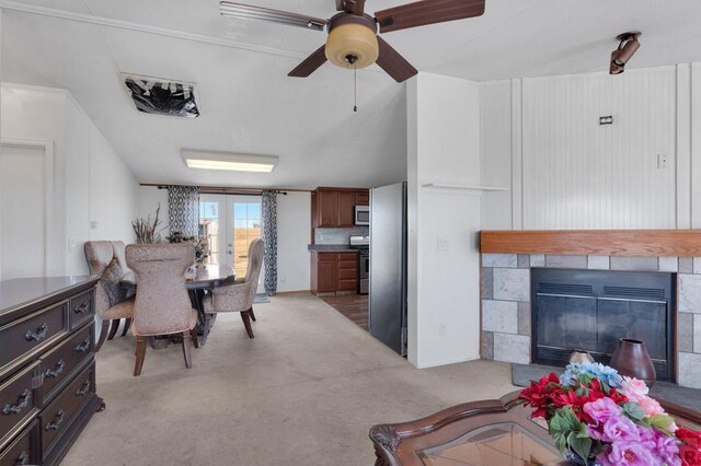 dining area featuring light carpet, ceiling fan, french doors, and a fireplace