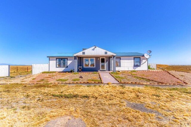 view of front of property featuring metal roof and fence