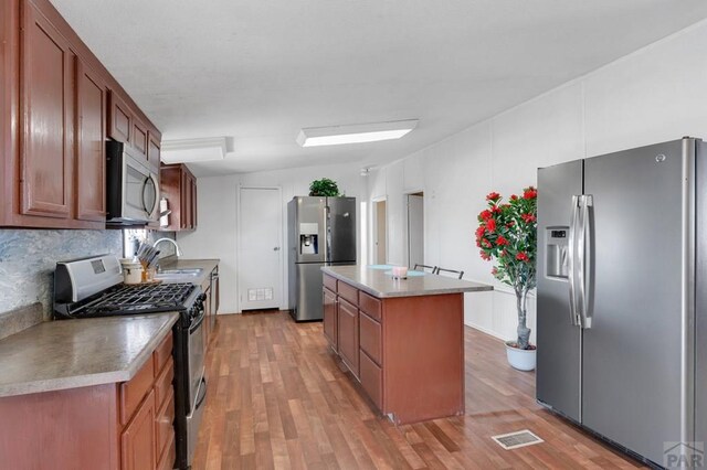 kitchen with light countertops, visible vents, appliances with stainless steel finishes, a sink, and an island with sink