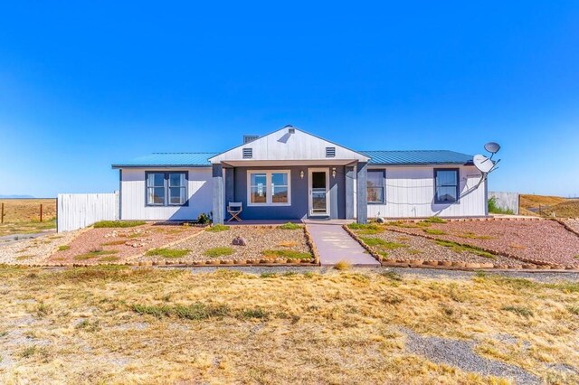 view of front of property featuring metal roof and fence