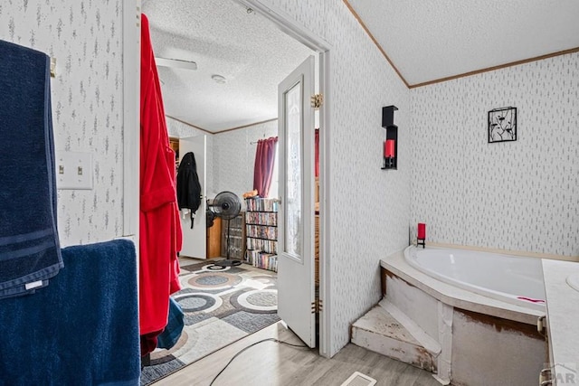 2100 W 100th Ave Unit 394, Thornton, CO 80260 - bathroom with a textured ceiling, wood finished floors, a garden tub, crown molding, and wallpapered walls