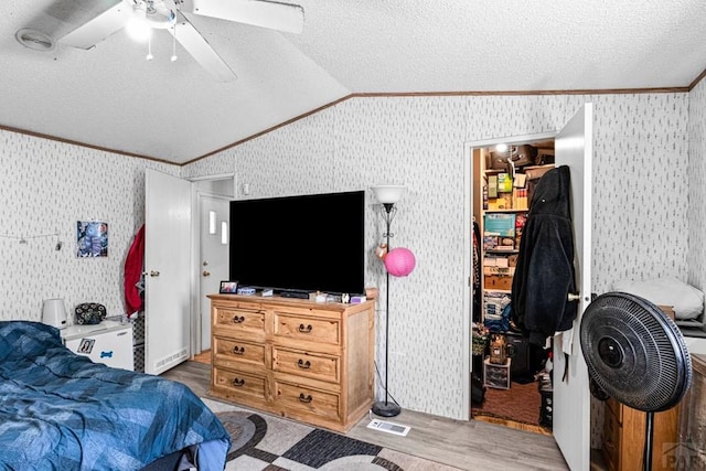 2100 W 100th Ave Unit 394, Thornton, CO 80260 - bedroom with ornamental molding, lofted ceiling, wood finished floors, a textured ceiling, and wallpapered walls