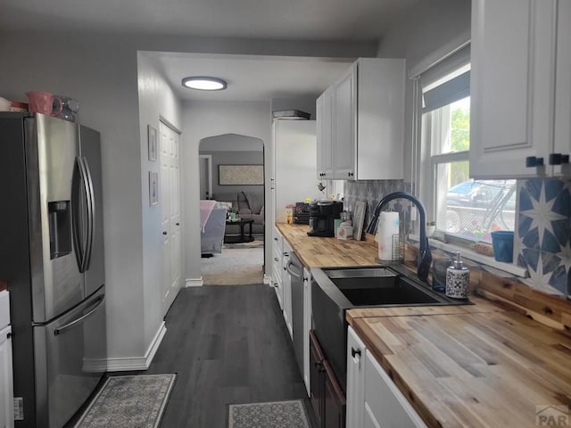 2602 3rd Ave, Pueblo, CO 81003 - kitchen with butcher block counters, appliances with stainless steel finishes, arched walkways, white cabinets, and backsplash